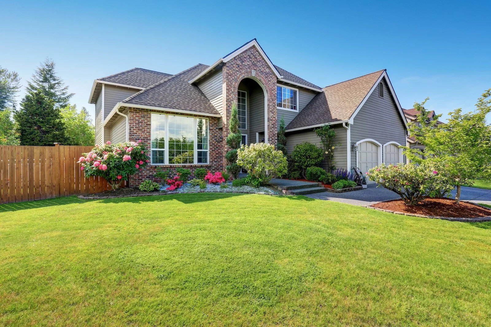 Brick home framed by a lush, freshly maintained green lawn
